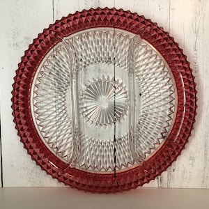 以下が含まれることがあります： ルビーレッドの縁が付いた透明なガラス製のサービングプラッター。プラッターは3つのセクションに分かれており、ダイヤモンド模様が特徴です。縁はテクスチャード加工された尖ったデザインです。軽食や前菜を提供する装飾品です。