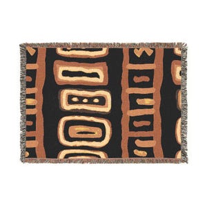 May include: Rectangular throw blanket with a black background and a repeating pattern of brown and tan shapes. The blanket has a fringed edge. The design is geometric and abstract.