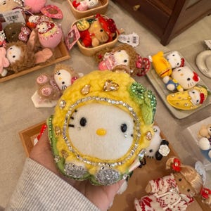 Könnte beinhalten: Eine weiße Keramik-Tasse mit schwarzem Henkel und dem Text "But First, Coffee" in fetter, schwarzer Schrift. Die Tasse steht vor einem verschwommenen Hintergrund, der eine gemütliche Umgebung suggeriert.