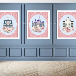 Puede incluir: Tres impresiones artísticas enmarcadas con ilustraciones arquitectónicas. Cada impresión muestra un diseño de edificio dentro de un óvalo azul claro, rodeado por un borde decorativo rosa y acentos florales. Las impresiones se exhiben en una pared azul.