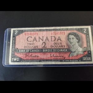 May include: A two-dollar Canadian banknote, with the text "CANADA" and "TWO DOLLARS" in English and French. The bill displays a portrait of a woman and the text "BANK OF CANADA - BANQUE DU CANADA".