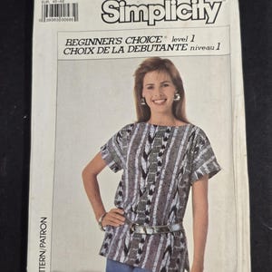 May include: A Simplicity sewing pattern envelope, number 7933, size LG (18-20). The front features a photograph of a top with a black, white, and grey abstract vertical pattern, short sleeves, and a belt. Text includes Beginner's Choice level 1.