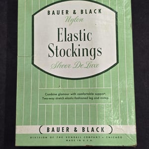 May include: A vintage box of Bauer & Black Nylon Elastic Stockings. The box is light green with vertical stripes and features the brand name and product description in a white and dark green design. The text reads "Sheer De Luxe".