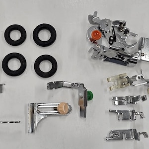 May include: A collection of sewing machine accessories including four black rubber rings, a complex metal buttonhole foot with an orange dial, a metal quilting guide, an adjustable edge guide with a beige knob, and four various metal presser feet.