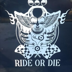 May include: White graphic of a skull with wings, a motor, and checkered flags on a black background. The text "RIDE OR DIE" is displayed below the skull. The design is likely for motorcycle enthusiasts.