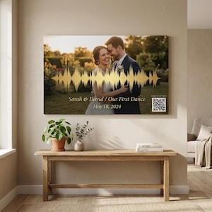 May include: A canvas print featuring a couple, with a golden soundwave design overlaid. The text reads "Sarah & David / Our First Dance" and "May 18, 2024". A QR code is in the lower right corner.