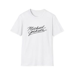 Op de afbeelding: Wit T-shirt met ronde hals en korte mouwen. De voorkant is voorzien van de naam "Michael Jackson" in zwart cursief schrift. Dit casual topje is een eenvoudig maar stijlvol kledingstuk, geschikt voor dagelijks gebruik. De tekst is gecentreerd.