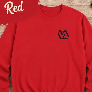 May include: A bright red crewneck sweatshirt featuring a small black geometric logo on the left chest. The word Red is printed in white script over a red brushstroke graphic in the upper left corner of the garment, which has long sleeves.