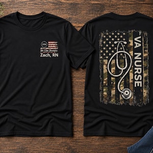 May include: A black t-shirt featuring a small American flag graphic with the text "We The People" and "Zach, RN" on the front left chest. The back displays a large distressed camouflage American flag with a stethoscope and the text "VA NURSE".