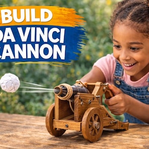 Op de afbeelding: Een houten Da Vinci kanon speelgoed met een papieren bal projectiel. Het kanon is bruin met zwarte accenten en heeft een touwdetail. De tekst "BUILD DA VINCI CANNON" staat linksboven. Een jong meisje lacht en bedient het speelgoed.