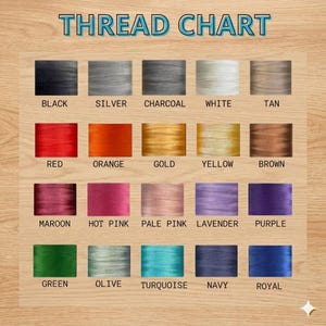 May include: A thread chart with a wooden background displays a variety of thread colors. The chart includes colors such as black, silver, charcoal, white, tan, red, orange, gold, yellow, brown, maroon, hot pink, pale pink, lavender, purple, green, olive, turquoise, navy, and royal.