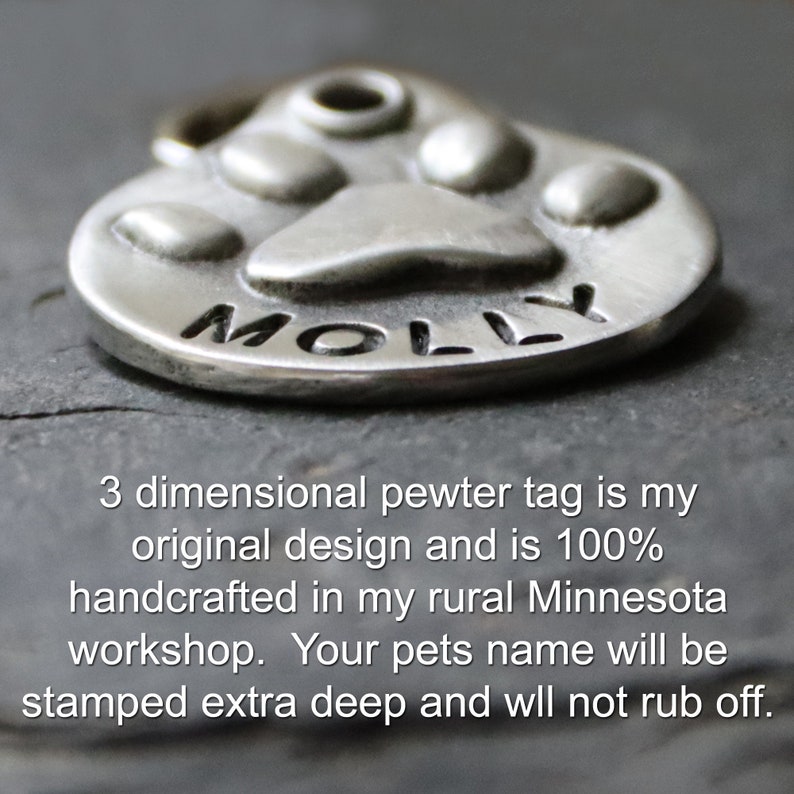 May include: A silver paw print pet tag with the name "MOLLY" engraved on it. The tag is 3-dimensional and handcrafted in a rural Minnesota workshop.