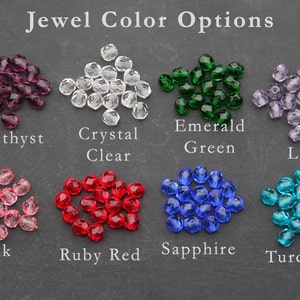 May include: Assortment of jewel tones in crystal beads, including amethyst, crystal clear, emerald green, lilac, pink, ruby red, sapphire, and turquoise.