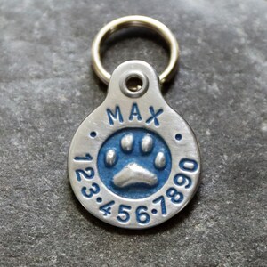 May include: Silver dog tag with a blue paw print and the name "MAX" and numbers 123.456.7890.