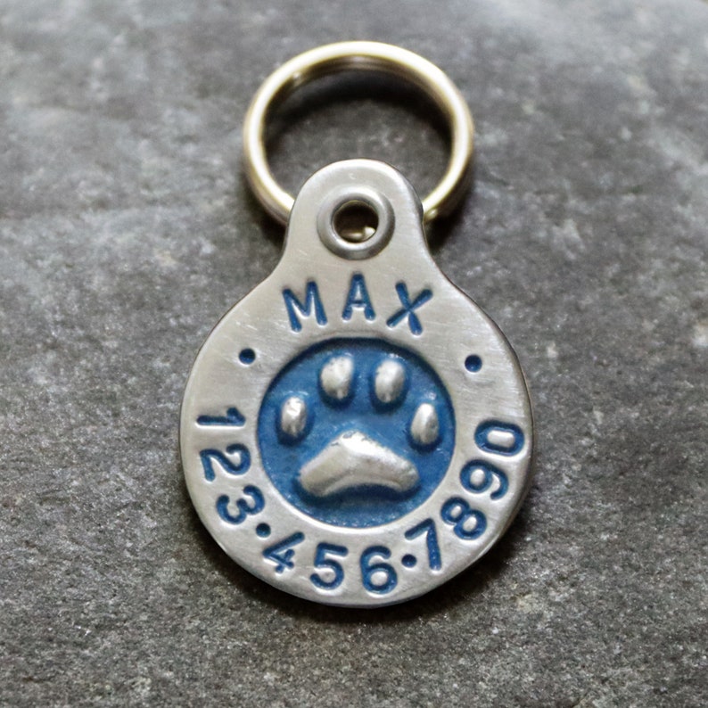 May include: Silver dog tag with a blue paw print and the name "MAX" and numbers 123.456.7890.