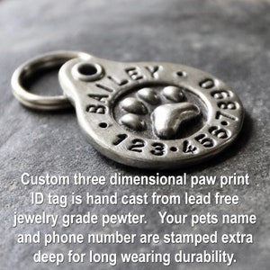 May include: Silver paw print pet ID tag with the name "BAILEY" and phone number "123-456789" engraved. The tag is hand cast from lead-free pewter.