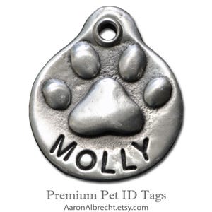 May include: Silver pet ID tag with a paw print design and the name "MOLLY" engraved in black lettering. Premium Pet ID Tags.