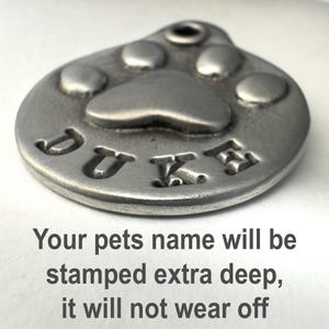 May include: Silver-toned pet ID tag with a paw print design and the name "DUKE" engraved on it.