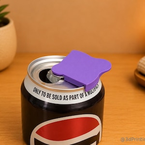May include: A purple plastic soda can cover attached to the top of a black and red aluminum beverage can. The can features the printed text "ONLY TO BE SOLD AS PART OF A MULTIPACK" along the upper rim, and the watermark "@3dPrintingLabDE".
