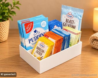 May include: A white rectangular plastic organizer with three internal compartments filled with various baking ingredient packets. The packets include blue Pudding, yellow Vanillin-Zucker, orange, and light blue Blatt-Gelatine labels with text.