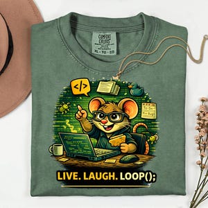 May include: Green Comfort Colors t-shirt with a cartoon mouse wearing glasses and working on a laptop. The mouse is surrounded by coding-related elements. The text "LIVE. LAUGH. LOOP();" is printed at the bottom.