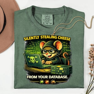 May include: Green t-shirt featuring a cartoon mouse in a hoodie and glasses, using a laptop with a skull and crossbones. The text says "SILENTLY STEALING CHEESE FROM YOUR DATABASE."