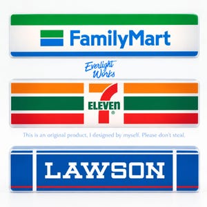 Może przedstawiać: Trzy prostokątne szyldy z logotypami marek. Górny szyld przedstawia zielono-biało-niebieskie logo FamilyMart. Środkowy szyld pokazuje pomarańczowo-zielono-czerwone logo 7-Eleven. Dolny szyld prezentuje niebiesko-białe logo LAWSON.