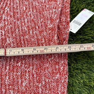May include: Close-up of a red and white knit fabric. A measuring tape shows the fabric is approximately 24 inches wide. A price tag is attached to the fabric. The fabric has a textured appearance.