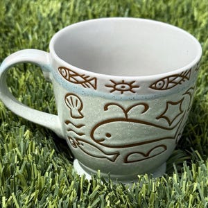 May include: A handmade wooden sign with the text "Welcome" in a handwritten style. The sign is painted white with a distressed finish and features a small, decorative heart. It is designed for indoor or outdoor use.