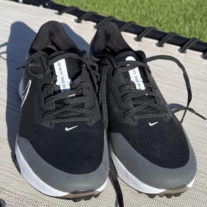 May include: Pair of black and gray athletic shoes with white soles. The shoes have black laces and the Nike swoosh logo in white. The text "INFINITY TOUR NEXT" is visible on the tongue of each shoe.