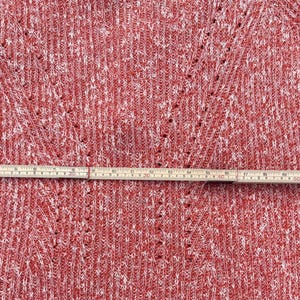 May include: Red and white knit sweater with a V-neck design. A wooden ruler is laid across the sweater, measuring approximately 24 inches. The sweater has a textured pattern and a tag attached.