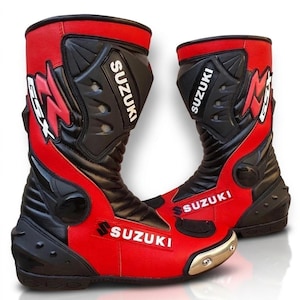 Peut inclure: Paire de bottes de moto rouges et noires avec le logo Suzuki. Les bottes ont une conception montante avec des panneaux renforcés et un embout doré. Conçues pour la protection et la performance.