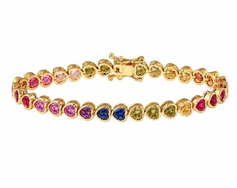 May include: A gold-tone bracelet featuring a continuous row of heart-shaped gemstones in a vibrant rainbow spectrum of colors including red, pink, purple, blue, yellow, and green. The bracelet is secured with a rectangular box clasp closure.