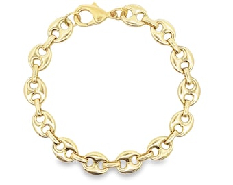 May include: A gold-colored chain bracelet with a lobster clasp. The bracelet features a series of oval-shaped links, each with a central indentation, creating a bean-like appearance. The bracelet is displayed against a white background.