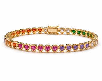May include: A gold-tone tennis bracelet featuring a continuous row of heart-shaped gemstones in a vibrant rainbow color gradient, including red, orange, pink, purple, green, and clear stones, secured with a rectangular box clasp closure.