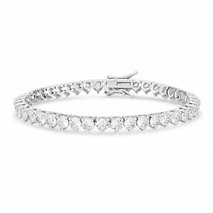 May include: A silver-toned tennis bracelet featuring a continuous row of round, clear, faceted stones set in a metallic frame. The bracelet includes a secure box clasp mechanism with a safety latch, creating a uniform and circular design.