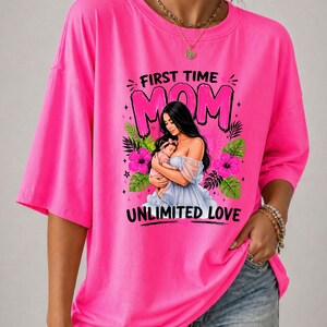 Puede incluir: Una camiseta de color rosa neón brillante con un estampado gráfico de una persona sosteniendo a un bebé. El texto dice FIRST TIME MOM y UNLIMITED LOVE. El diseño incluye flores de hibisco rosas y hojas tropicales verdes.