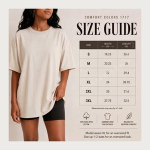 May include: A woman wearing a beige Comfort Colors 1717 t-shirt and black shorts. The image includes a size guide with measurements in inches for sizes S to 3XL. The shirt is made of 100% ring-spun cotton and is garment-dyed for softness.