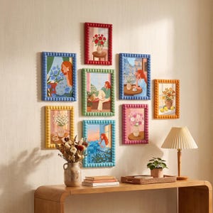 May include: A gallery wall arrangement of eight rectangular picture frames with beaded edges in various colors, each containing a colorful illustration of a person or flowers, displayed above a wooden console table with a lamp and vase.