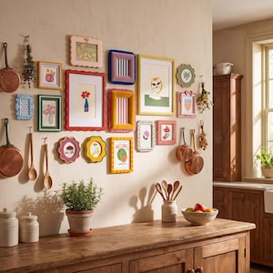 Może przedstawiać: Ściana galeria z r&oacute;żnymi kolorowymi ramkami na zdjęcia z ilustracjami, w tym arbuzem z napisem MELONE LA FRUTTA, obok miedzianych patelni, drewnianych łyżek, rośliny doniczkowej i miski z owocami na drewnianym blacie kuchennym.