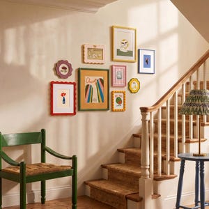 Può includere: Una parete galleria composta da nove cornici rettangolari e smerlate di vari colori, tra cui rosso, verde, rosa e giallo. Le cornici contengono diverse illustrazioni, tra cui una stampa di Chicago, un'anguria e un gatto.