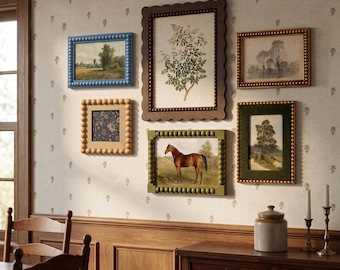May include: A gallery wall arrangement featuring five framed art prints. The frames include a blue beaded frame, a large dark brown scalloped frame, a gold beaded frame, a light wood beaded frame, and a green beaded frame.