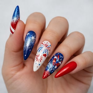 May include: A hand displays long, almond-shaped nails with a patriotic theme. The nails feature designs of fireworks, stars, and stripes in red, white, and blue, with glitter accents. The nails are painted with gel polish.