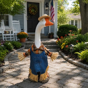 May include: A decorative goose statue wearing a straw hat, an orange and brown plaid shirt, and blue denim overalls with a front pocket and yellow fringe trim at the hem and sleeves. The goose has a white body and a bright orange beak.