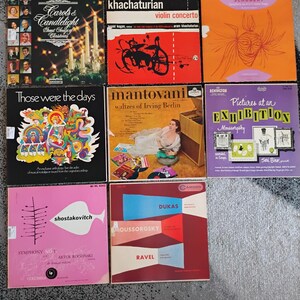 May include: A collection of vintage vinyl records featuring album covers with various designs and text. The records include classical music, Christmas carols, and other genres. The covers display vibrant colors and artistic illustrations.