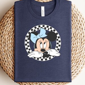 Navy Bella Canvas tee with Minnie Mouse character illustration in a checkered circle frame wearing a blue bow.