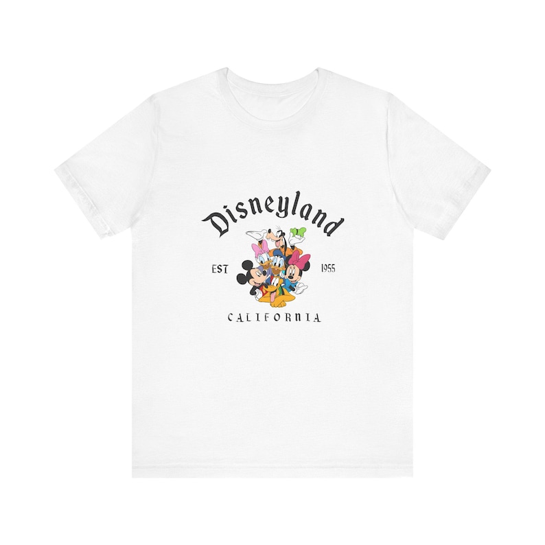 White unisex tee featuring classic Disney characters with "Disneyland EST 1955 California" text graphic centered on chest.