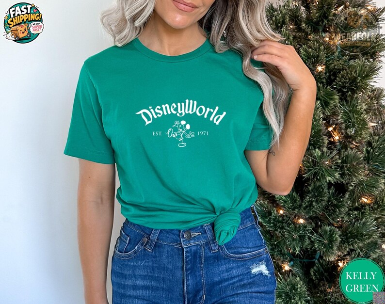 Woman wearing a kelly green Bella Canvas tee with white "DisneyWorld EST 1971" text and Mickey graphic on the front.