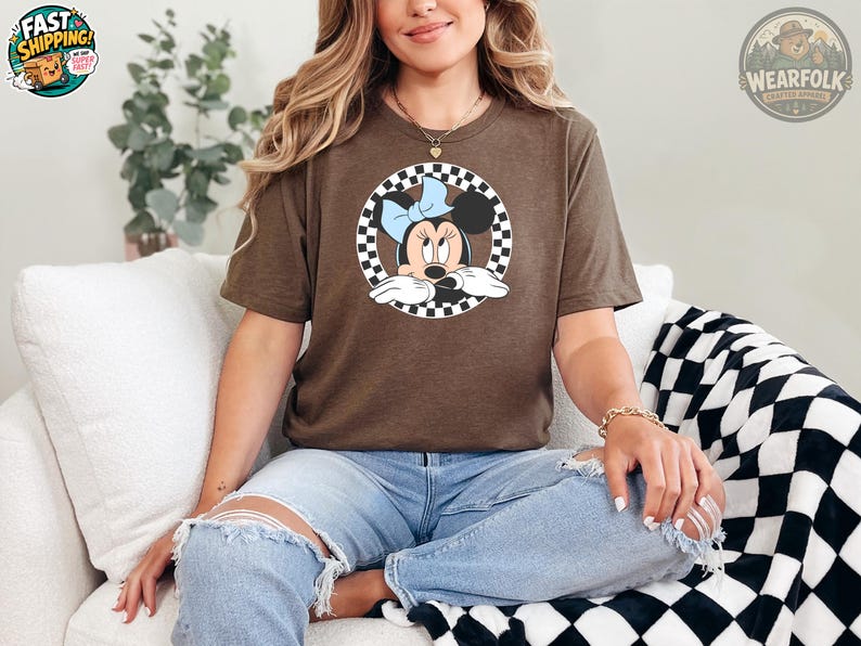 Woman wearing a brown Bella Canvas tee with Minnie Mouse graphic inside a black and white checkered circle design on the front.