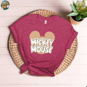 Heather berry tee with Mickey Mouse ears graphic and white text reading "Mickey Mouse" in retro style.